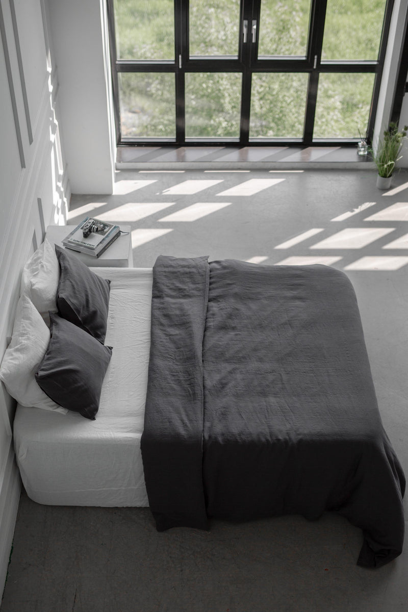 Side Top View Of Bed With Charcoal Linen Bedding Set In A White Spacious Room